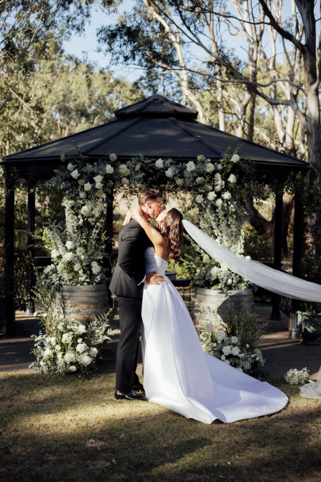 Mon and Ben’s wedding at Clyde Park was nothing short of magical!
*
Nestled among the stunning vineyards and breath-taking landscapes, their celebration was a true testament to the beauty of love and nature. With a classic palette of white and green florals, our talented florists worked with the couple to design a floral scheme that perfectly complemented the idyllic surroundings. 
*
A standout feature of the ceremony florals was the creative use of wine barrels. They not only provided rustic charm but also served as the perfect base for the floral arrangements. Full florals and foliage sat upon and around the base of the barrels, enhancing the overall aesthetic of the ceremony location. The gorgeous floral installation atop the pergola added an extra touch of elegance.
*
The bridal party’s florals were thoughtfully designed to harmonise with the overall scheme, ensuring that every detail was cohesive and beautiful.
*
*
*
Couple @monstevanja & @benjygeall
Photographer @_wildheart.photography
Venue @clydeparkwines
Accessories @brettsjewellers
Cake Maker @clydeparkwines
Caterer @clydeparkwines
Celebrant @kateurencelebrant
DJ & Music @geelong_entertainment
Bridal Gown @marianahardwick
Engagement Ring @brettsjewellers
Florists & Styling @elderberryevents_
Hair Stylist @ameliarosehairstylist
MC @kateurencelebrant
Make Up Artist @montannayatesmua
Suit @joeblackofficial
Transport @murrellgroup
Bridesmaids @billy_j_boutique